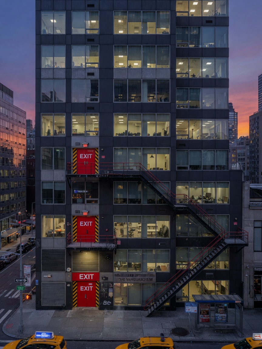 Ultra-realistic 8K photograph of a modern NYC high-rise building exterior at dusk with glowing windows and prominent fire exit doors, cinematic lighting, sharp architectural details, New York City atmosphere